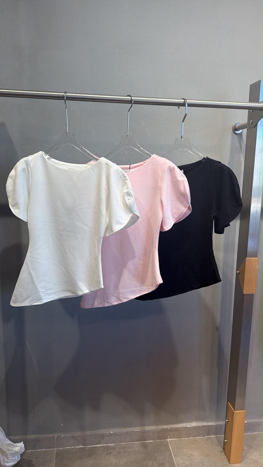 חולצה שרוול בלון חולצות עם שרוולים תפוחים תלויות על קולבים.